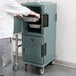 A man standing next to a Cambro Ultra Camcart for food pans.