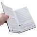 A hand holding an open Restaurant Manager's Handbook.
