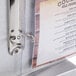 An Alumitique aluminum menu tent with a brushed finish holding a menu on a table.