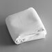 A folded white rectangular Intedge table cover on a gray surface.
