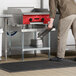 A man standing near a Regency stainless steel equipment stand with a galvanized undershelf.