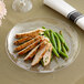 A WNA Comet clear plastic plate with sliced chicken and green beans on it.