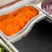 A stainless steel adapter bar with a tray of shredded carrots and onions.