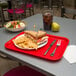 A Carlisle red fast food tray with a sandwich and chips on it.