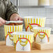 A person cutting chicken into a yellow and white Choice chicken bucket.
