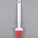 A white Carlisle Sparta basting brush with an orange silicone bristle and hook.