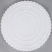 A white plastic Wilton cake separator plate with scalloped edges.