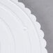 A white plastic Wilton cake separator plate with scalloped edges.