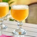 Two Anchor Hocking schooner glasses of orange liquid on a table.