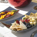 A Vollrath stainless steel curved platter with vegetables on a table.