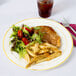 A Fineline ivory plastic plate with gold bands holding food with a drink and a fork.