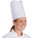 A woman wearing a white Royal Paper disposable chef hat.