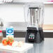 A Waring commercial blender on a counter with a bowl of vegetables and spices.