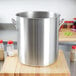 A large silver Vollrath stainless steel stock pot on a wooden surface.