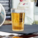 A Fineline clear plastic shooter glass filled with brown liquid on a table in a bar.