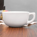 A close-up of a Tuxton white china cappuccino cup.