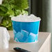 A blue disposable paper ice bucket filled with ice cubes.