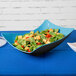 A salad in a blue and black Brasilia melamine bowl.