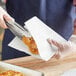 A person using tongs to put a pretzel in a Choice pretzel bag.