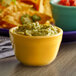 A yellow Tuxton China bouillon bowl filled with guacamole.