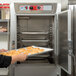 A woman using a Metro holding cabinet with Dutch doors to bake pastries.