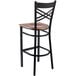 A Lancaster Table & Seating black cross back bar stool with a wooden seat.