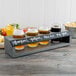 A Cal-Mil gray wood tasting caddy with four glasses of beer on a table.