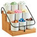 A Cal-Mil bamboo condiment station on a hotel counter with white containers of sugar, tea, and orange and blue cups.