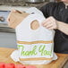 A woman holding a white LK Packaging plastic take out bag with green "Thank You" text.