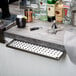 A Regency stainless steel underbar mount beer drip tray on a bar counter.