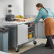 A woman in an apron using a Beverage-Air worktop freezer in a kitchen.