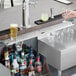 A person holding a glass of beer under a Regency stainless steel beer drip tray.