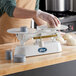 A person using an Edlund baker's dough scale to weigh dough on a counter.