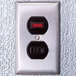 A metal wall switch with red and black numbers on a wall in a walk-in cooler.