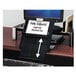 A black plastic Fellowes desktop copyholder on a desk with a computer and a book.