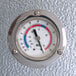 A close-up of the temperature gauge on a metal surface on a Kolpak walk-in freezer.