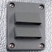 A grey metal rectangular wall plate with two holes.