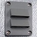 A grey metal rectangular wall plate with metal corners and two holes.