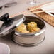 A container of Choice 5" Perforated Round Steamer Paper on a table with a pot of food.