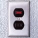 A metal wall switch with red and black numbers on a Kolpak indoor walk-in cooler.