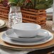 An American Metalcraft white melamine bouillon cup on a table with a white plate and bowl.