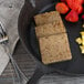 A close-up of a square brown piece of Kunzler Scrapple on a plate with a fork.