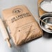 A bag of King Arthur Flour Sir Lancelot Hi-Gluten Flour next to bowls and a wooden spoon.