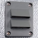 A grey rectangular device with metal corners and two holes.
