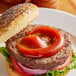 A burger with a bun, lettuce, tomato, and Heinz ketchup on a plate.