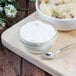 A bowl of mashed potatoes with a spoon next to it.