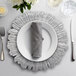 A 10 Strawberry Street silver glass charger plate with silverware on a table.