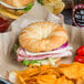 A Hadley Farms croissant sandwich with ham and cheese on a plate with chips.