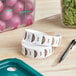 A roll of Noble Products Thursday day of the week labels on a table next to a pen and a container of salad.