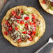 A slate with a fork and two small tacos with Father Sam's Bakery flour tortillas filled with meat and vegetables.